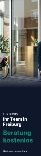 Skyscraper mit dem Teamfoto, Ausschnitt aus der Bildmitte: Glasfassade und ein Fahrrad, keine Person.